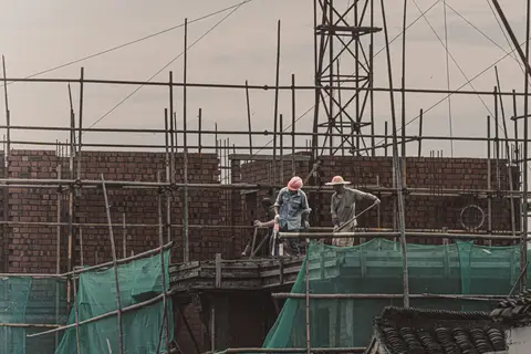 Two builders on scaffolding laying a brick wall